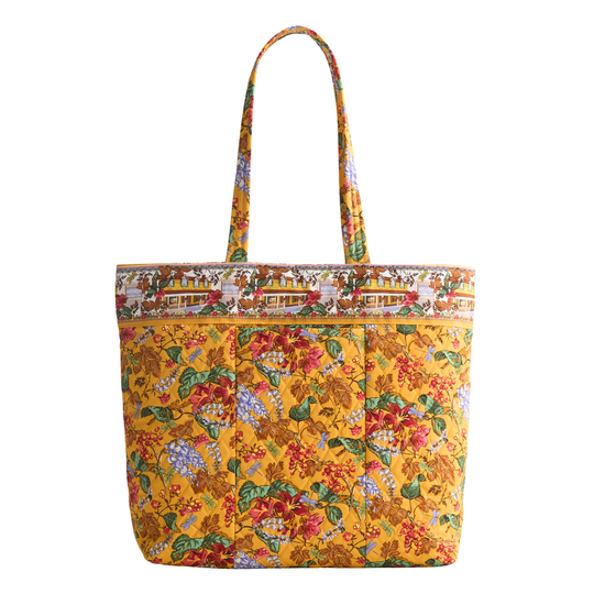 A structured tote bag with a vibrant floral print on a golden-yellow background, featuring two shoulder straps and a decorative printed border along the top.