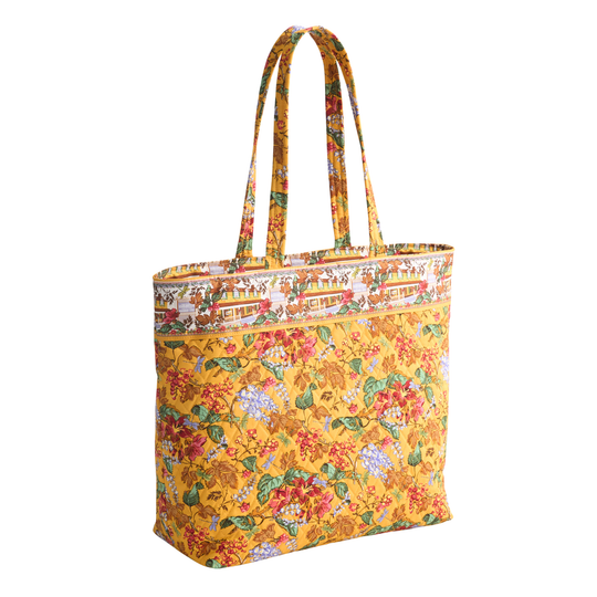 A yellow fabric tote bag with a colorful floral print and a decorative printed border near the top, shown on a plain white background.