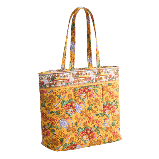 A yellow fabric tote bag with a colorful floral print and a decorative printed top band, shown on a plain white background.