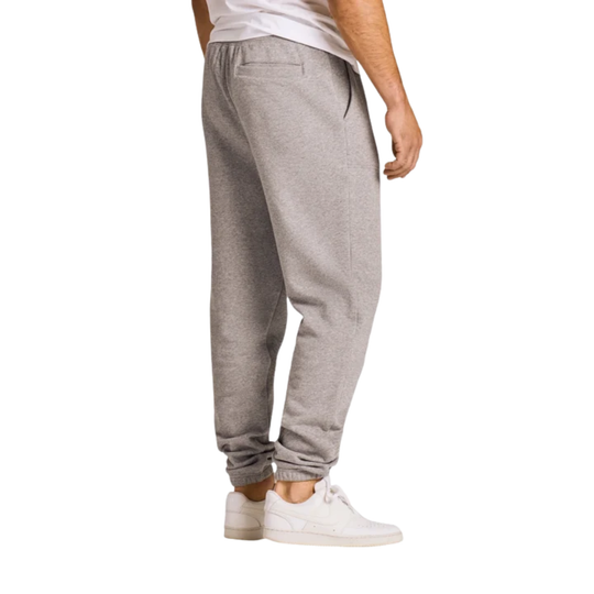 A person shown from the waist down wearing light heather gray jogger sweatpants with elastic cuffs and white sneakers, photographed against a plain white studio background.