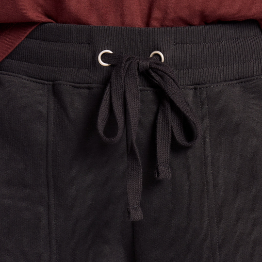 Black pants with a drawstring detail on a plain background