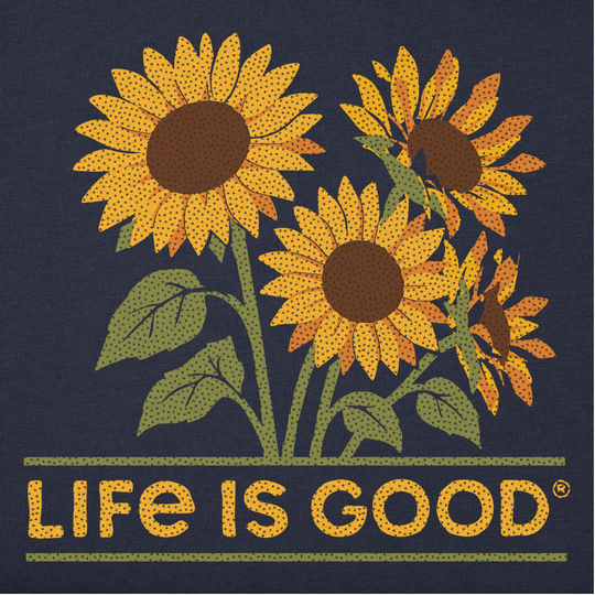 A square graphic print featuring four stylized sunflowers with yellow petals, brown centers, and green stems on a dark navy background. Below the flowers, the phrase 'LIFE IS GOOD' appears in large yellow dotted letters, with two thin green horizontal lines above and below the text.