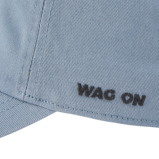 Close-up of a light blue denim cap with the embroidered text 'WAG ON' in black on the side, set against a plain white background.