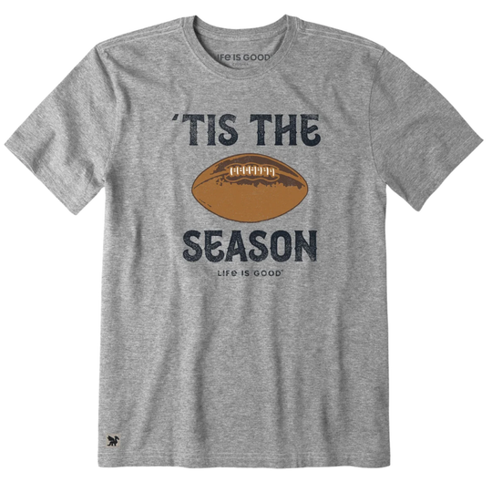 A heather gray crewneck t-shirt featuring a distressed graphic print of a brown football with the text 'TIS THE SEASON' and 'LIFE IS GOOD' underneath, displayed on a solid white background.