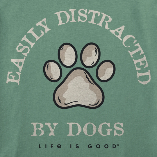 A close-up of a green graphic print featuring a large paw print in the center, with the words 'EASILY DISTRACTED BY DOGS' and 'LIFE IS GOOD' printed around it.