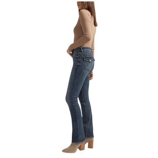 A woman modeling a fitted tan long-sleeve top and dark blue straight-leg jeans with beige ankle boots, shown against a plain white studio background.