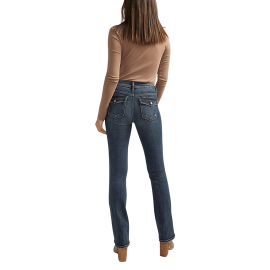 A woman shown from the back wearing dark blue straight-leg jeans, a tan long-sleeve top, and brown block-heel mules against a plain white background.