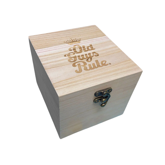 A square wooden gift box with a light natural wood grain finish, featuring the phrase 'Old Guys Rule' engraved on the lid in a warm brown tone, complete with a small crown icon above. The box is fitted with a small antique-style metal clasp on the front, set against a plain white background.