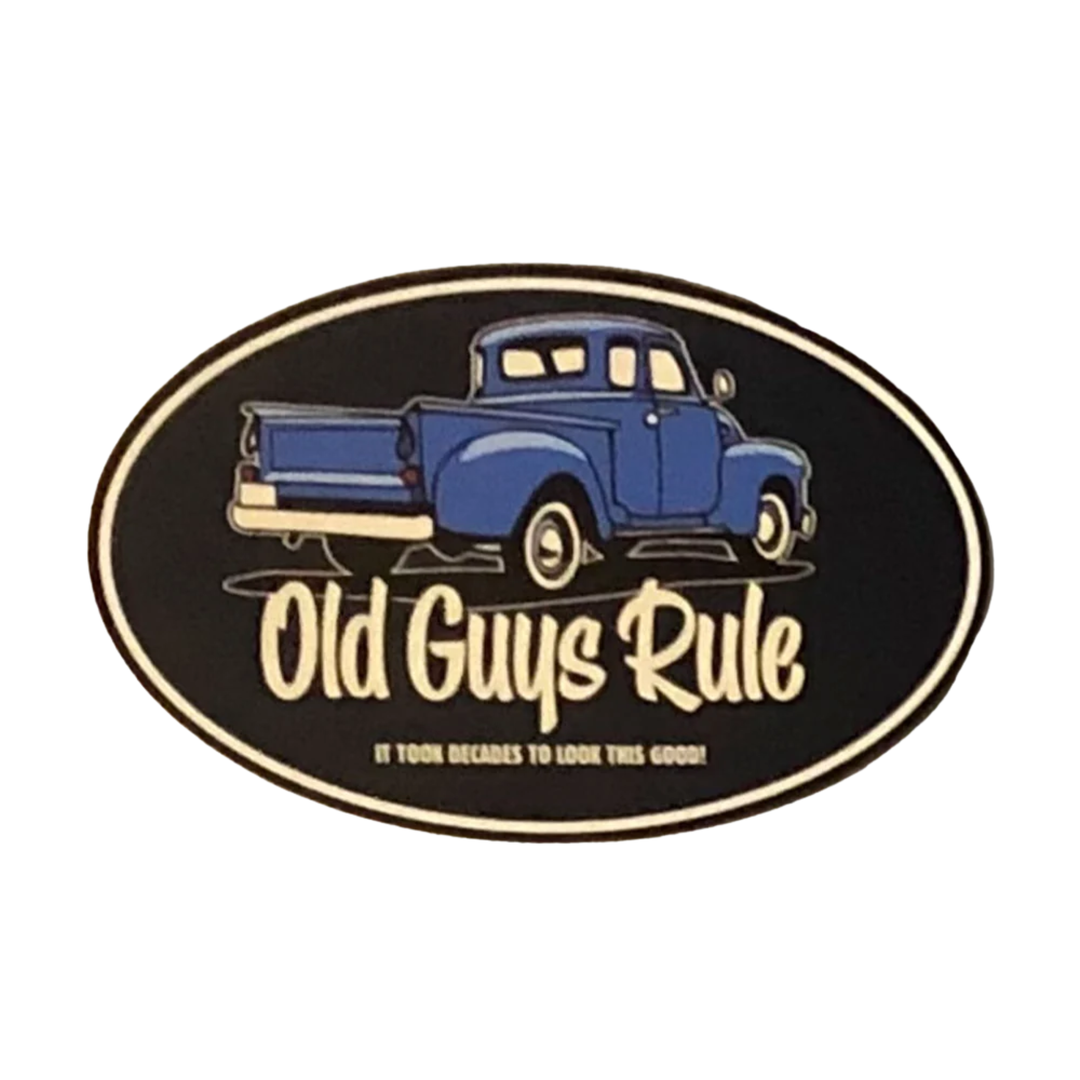 An oval black patch or sticker featuring a blue vintage pickup truck and the text 'Old Guys Rule' with smaller text below reading 'IT TAKES DECades TO LOOK THIS GOOD!' on a plain white background.