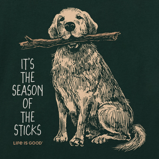 A dark green graphic print featuring a beige line-art illustration of a dog sitting and holding a stick in its mouth, with the text 'IT'S THE SEASON OF THE STICKS' and 'LIFE IS GOOD' printed below.