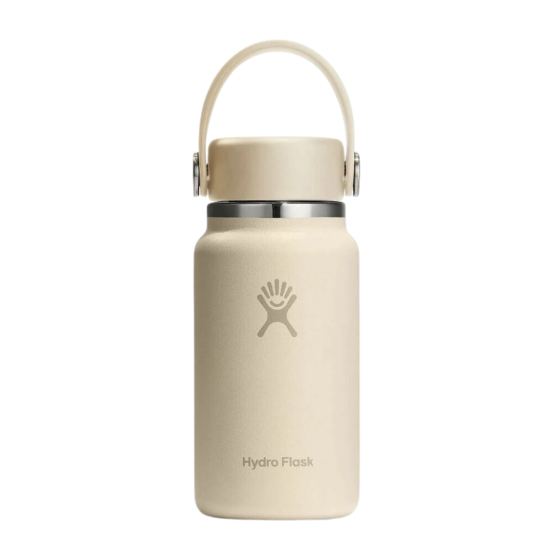 A Hydro Flask insulated water bottle in a light cream or off-white color, featuring a matching carrying loop lid and a silver metal collar, shown against a plain white background.