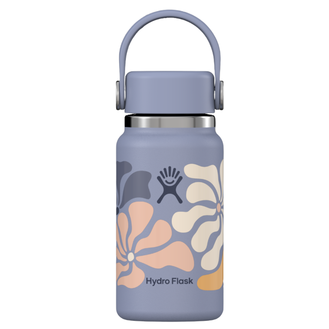 A Hydro Flask insulated water bottle in a muted lavender-purple color, decorated with retro-style floral patterns in peach, cream, and dark gray. The bottle features a matching purple carrying loop lid and a silver stainless steel collar, set against a plain white background.