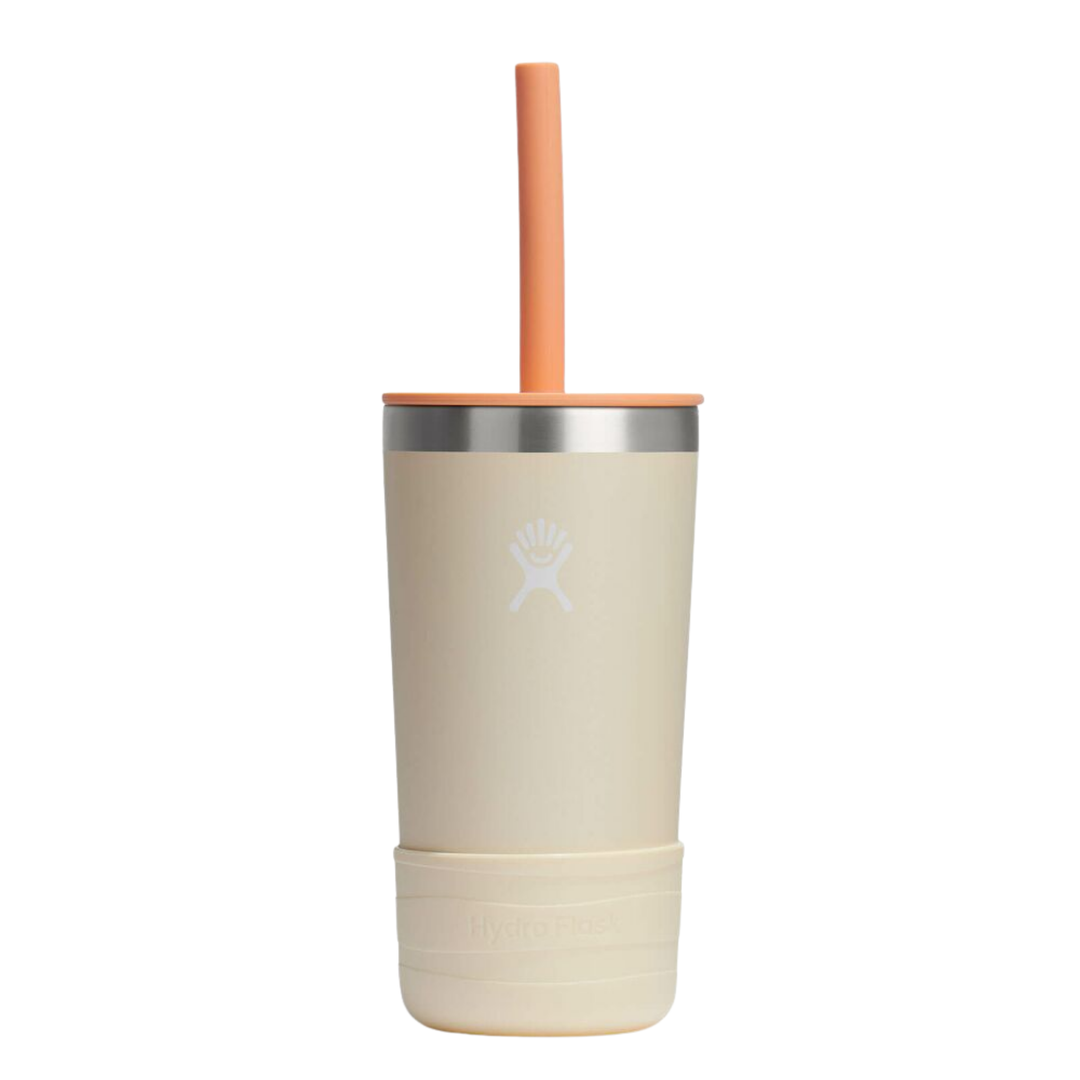 A cream-colored insulated travel tumbler with a silver metallic band, a matching cream lid, a light orange straw, and a textured cream base. The Hydro Flask logo is embossed on the front.