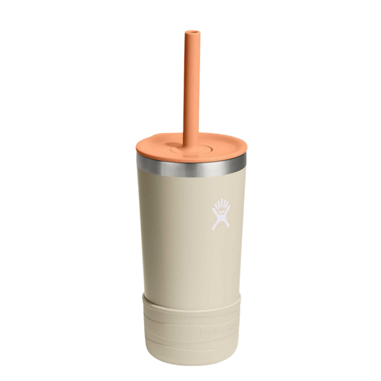 A 12 oz insulated travel tumbler in a light beige color, featuring a peach-colored lid and straw, a silver stainless steel band, and the white Hydro Flask logo on the front.