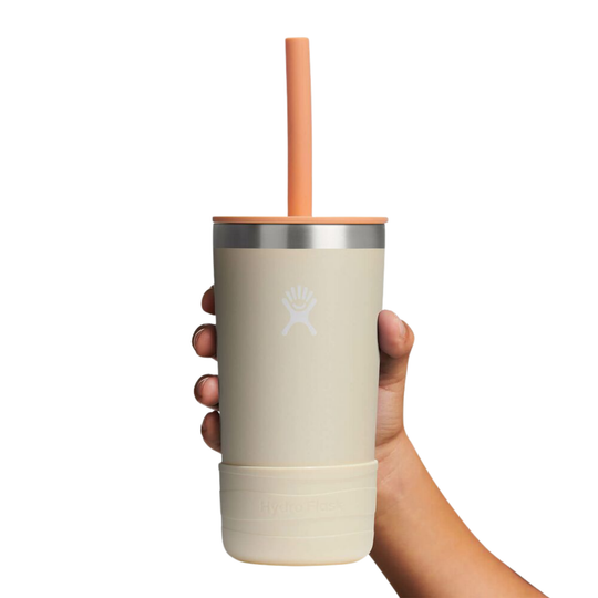 Beige tumbler with a straw held by a hand on a white background
