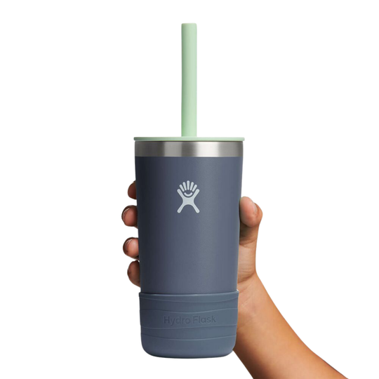 Hand holding a blue tumbler with a straw on a white background