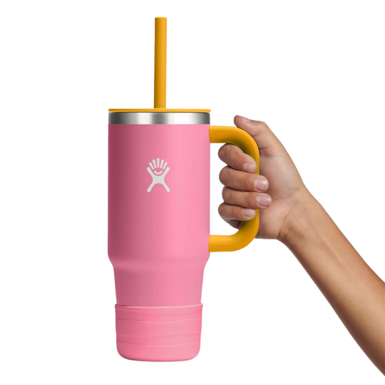 Pink mug with yellow handle and straw held by a hand on a white background