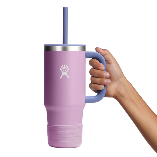 Purple mug with handle and straw held by a hand on a white background