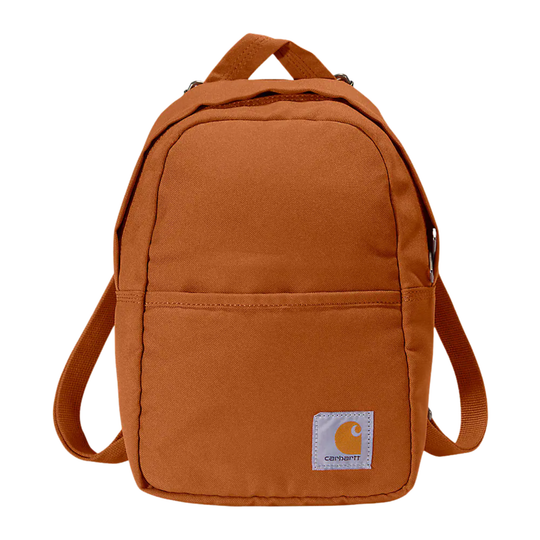 A classic Carhartt canvas backpack in a warm rust-orange color, featuring a front zippered pocket and the signature Carhartt patch on the lower right corner, set against a plain white background.