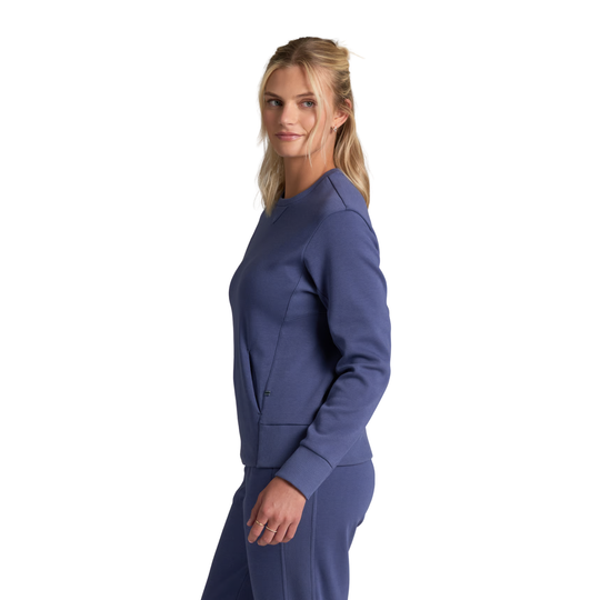 A woman modeling a matching navy blue lounge set, featuring a long-sleeve top and coordinating pants, shown from a side profile against a solid white background.