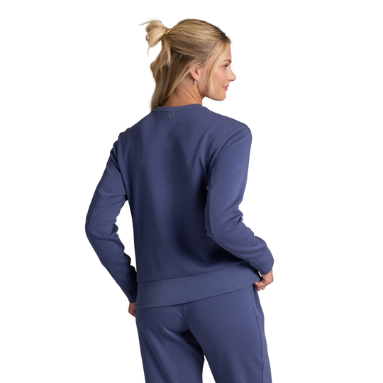 A woman with blonde hair in a ponytail is shown from the back wearing a matching navy blue sweatshirt and sweatpants set against a plain white background.