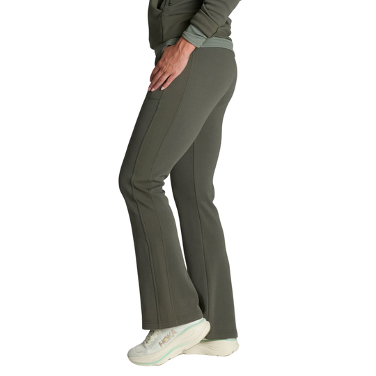 Side view of a person wearing olive green flared pants and a matching top, paired with white sneakers, against a plain white background.