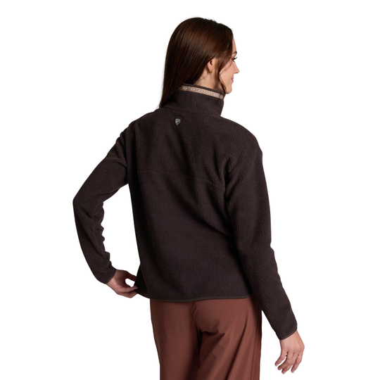 A woman shown from the back wearing a dark brown fleece pullover and brown pants against a plain white background.