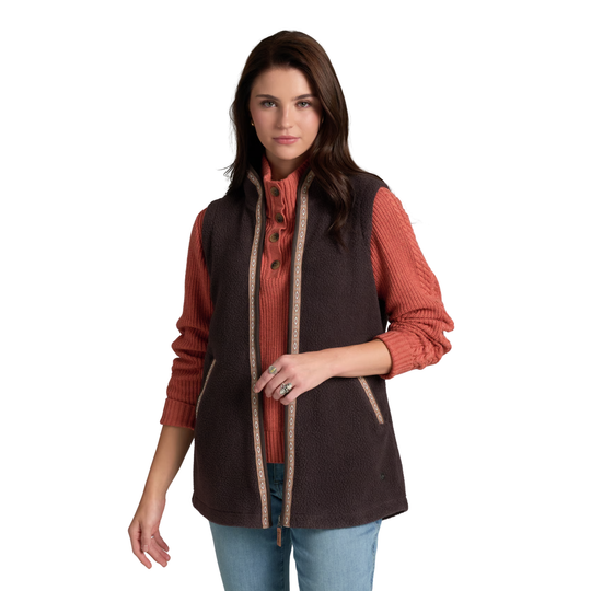 A woman modeling a dark brown fleece vest over a rust-orange ribbed knit top and blue jeans, photographed against a solid white background.