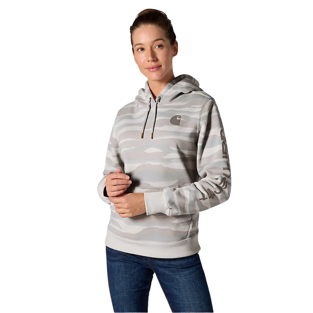 A woman modeling a light gray and white camouflage-patterned hoodie with a small Carhartt logo on the chest, paired with blue jeans, against a plain white background.