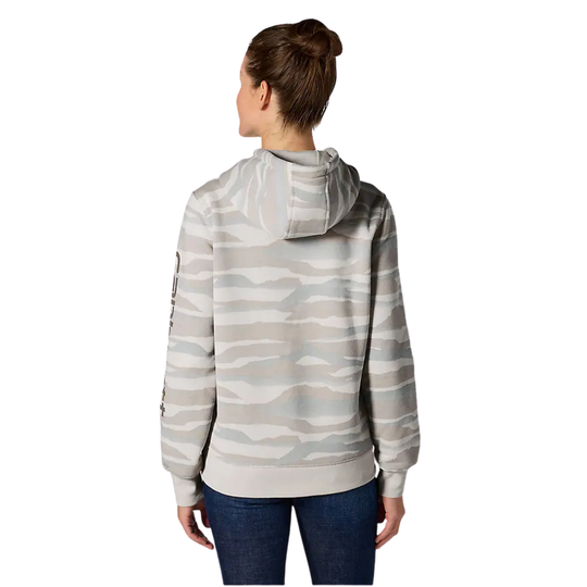 A woman viewed from the back wearing a light gray and beige wavy-striped hoodie with blue jeans, set against a plain white background.