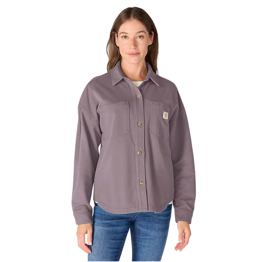 A woman modeling a Carhartt long-sleeve button-up work shirt in a dusty purple color, paired with blue jeans, against a plain white background.