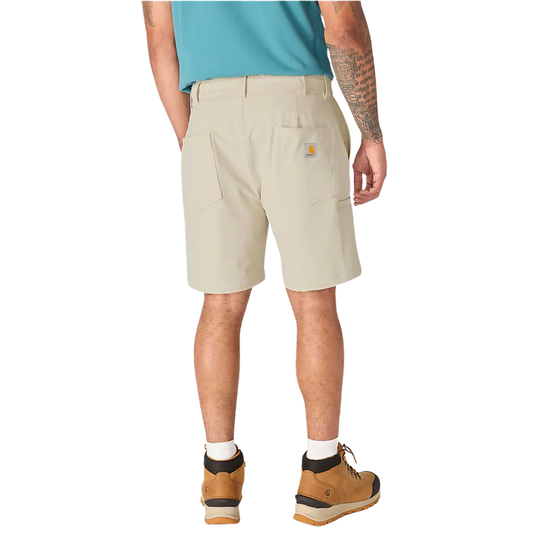 A man is shown from the back wearing light beige Carhartt work shorts, a teal t-shirt, and brown hiking boots against a plain white background.