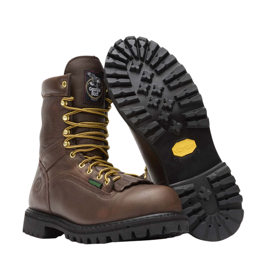 A pair of dark brown leather work boots with gold-colored metal eyelets and laces, shown from a three-quarters angle against a plain white background. Bottom of tread shown. Black Vibram sole.