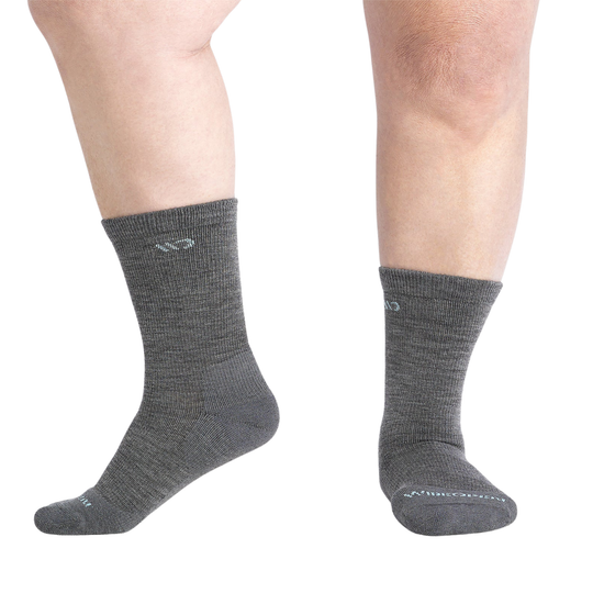 A pair of dark gray crew socks worn on a person's feet, shown against a plain white background.