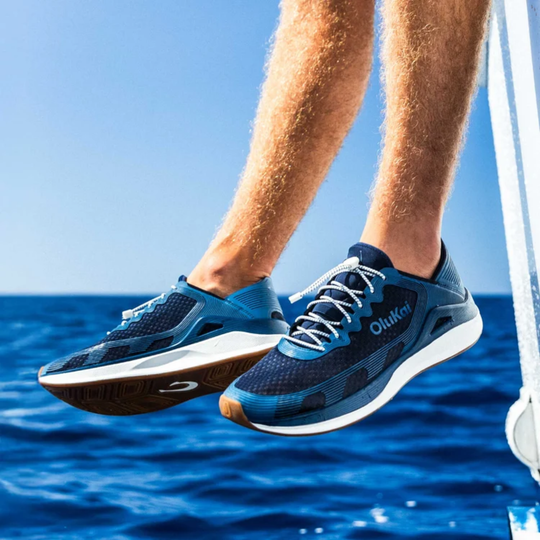  A pair of blue athletic sneakers on a male model with a water and boat in the background
