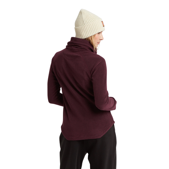 A woman shown from the back wearing a dark burgundy long-sleeve half-zip fleece, a cream ribbed knit beanie, and black pants, set against a plain white background.