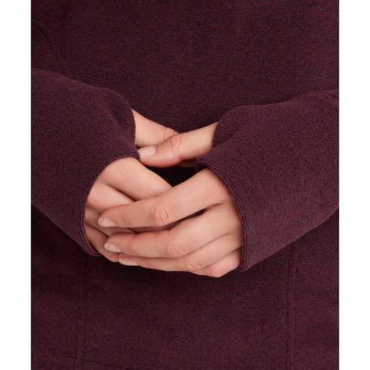 Close-up of a person wearing a textured knit sweater in a deep plum purple color, with their hands folded together in the center.