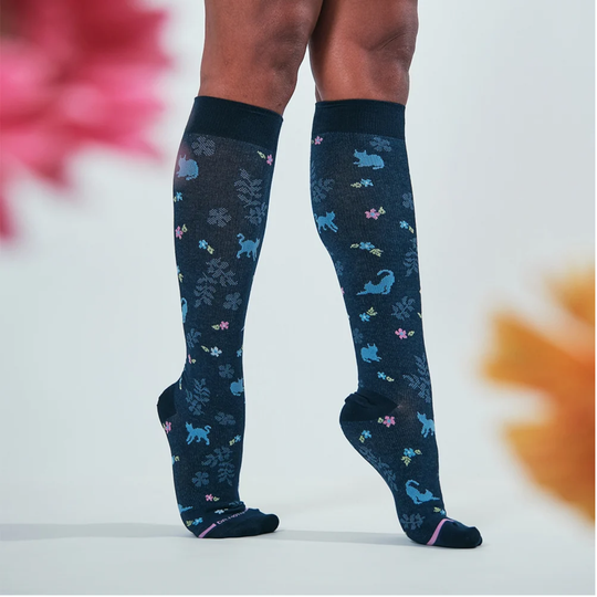 Navy knee-high socks with colorful animal pattern on a female model against a white background with blurred out flowers
