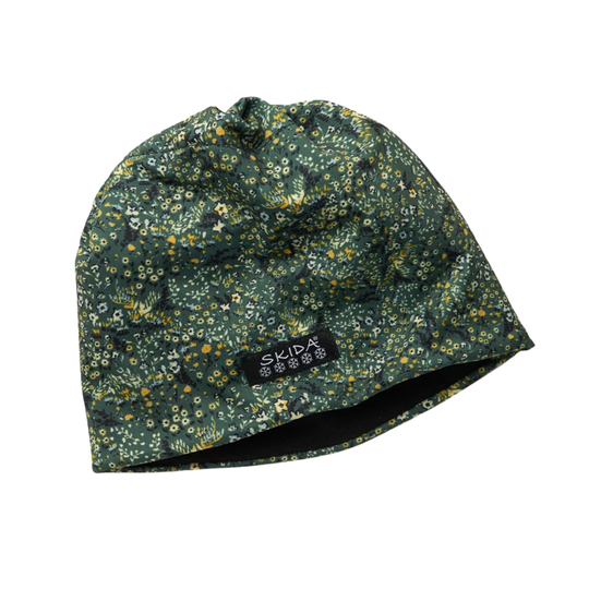 A dark green beanie hat with a dense yellow, white, and light green floral pattern, featuring a black brand label that reads 'skida'. The beanie is photographed on a clean white background.