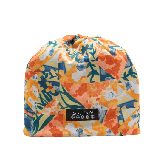 A drawstring pouch featuring a vibrant floral patchwork print in orange, yellow, blue, and green, with a black brand label reading 'SKIDA' on the front, set against a plain white background.