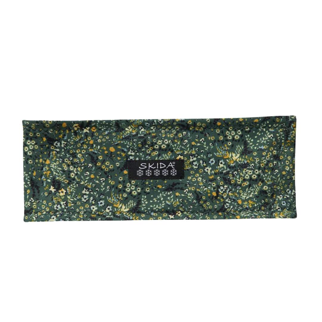 A rectangular dark green fabric pouch with a dense floral and botanical print, featuring a central black label with the brand name 'SKIDA'.