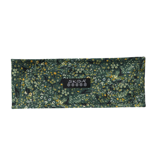 A rectangular dark green fabric pouch with a dense floral and botanical print, featuring a central black label with the brand name 'SKIDA'.