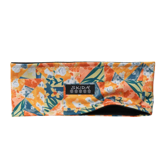 A rectangular headband with a vibrant orange, yellow, and teal abstract floral pattern, featuring a black brand label that reads 'SKIDA' in white text.