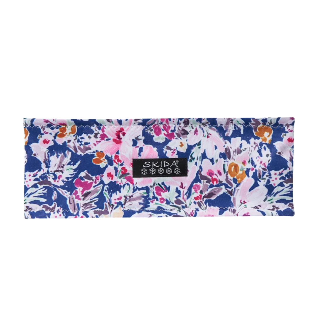 A rectangular fabric headband with a dense floral and botanical print in navy blue, pink, white, and orange, featuring a black SKIDA brand label in the center.