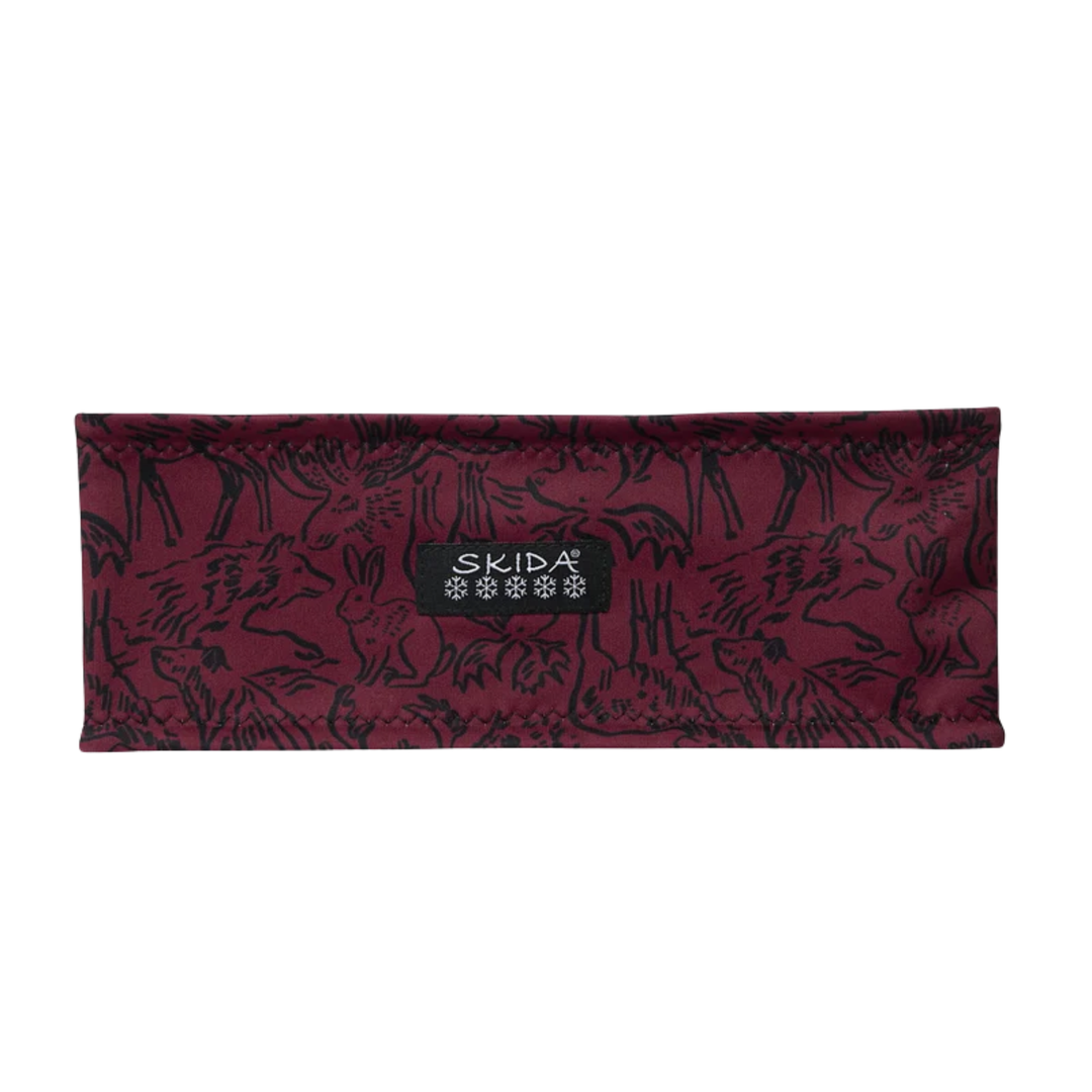 A rectangular fabric pouch or sleeve in deep burgundy with a black animal print pattern, featuring a central black label with the brand name SKIDA.