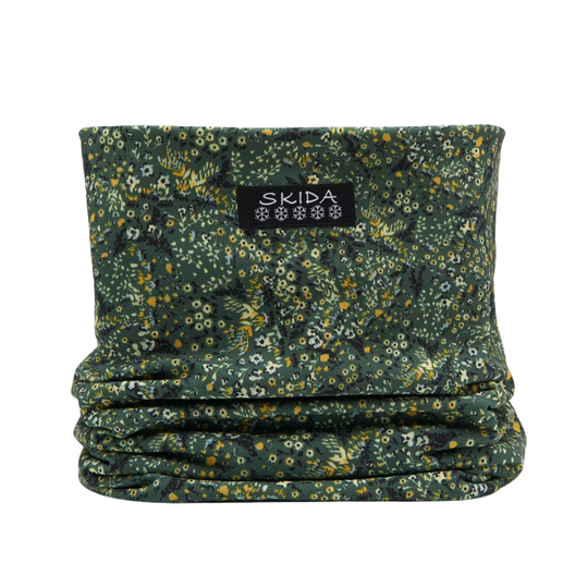 A dark green fleece neck gaiter with a dense yellow, white, and light green floral pattern, featuring a black brand label that reads 'SKIDA'.
