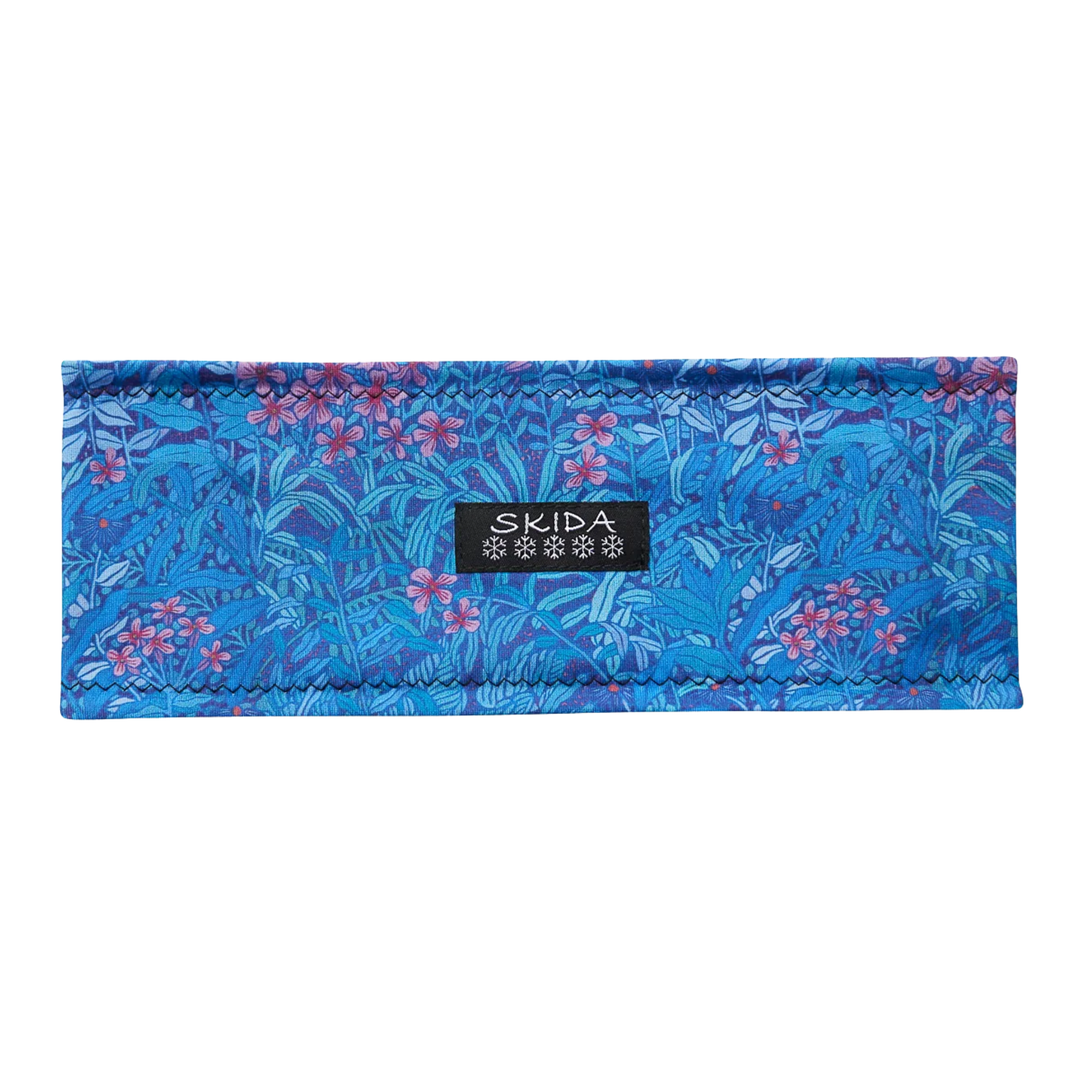 A blue patterned fabric headband with a floral print and a black SKIDA brand label in the center, shown against a plain white background.