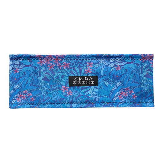 A blue patterned fabric headband with a floral print and a black SKIDA brand label in the center, shown against a plain white background.