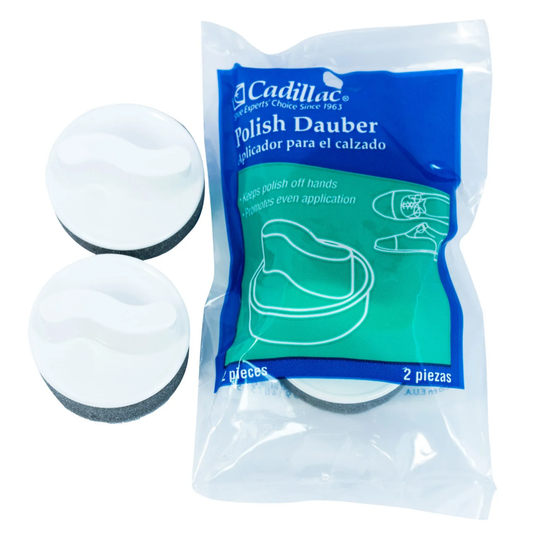 Two white and gray circular shoe polish daubers shown next to their blue and green branded retail packaging on a white background.