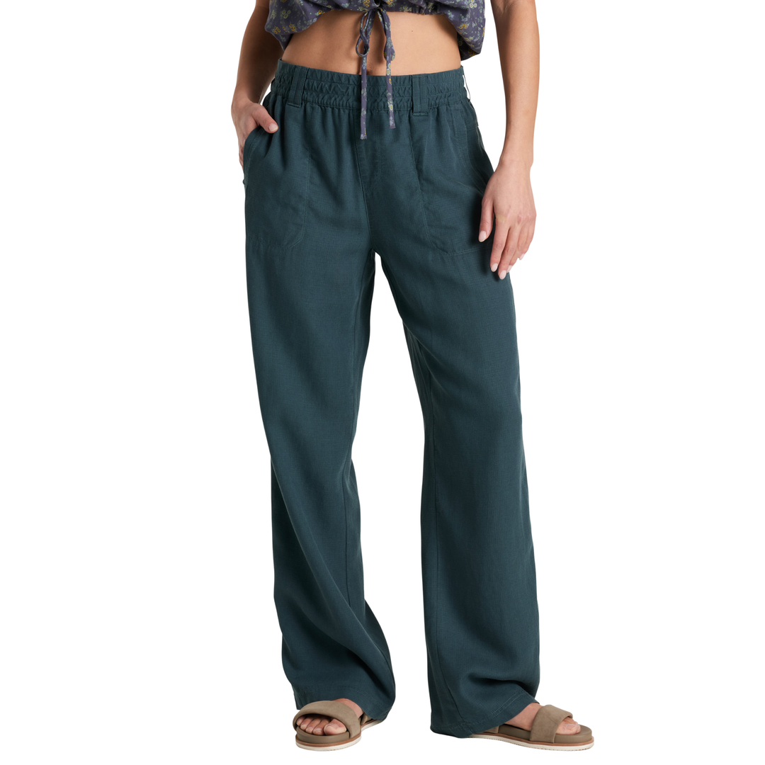 A front view of a person wearing dark teal wide-leg pants with a matching patterned top and brown slide sandals, shown against a plain white background.